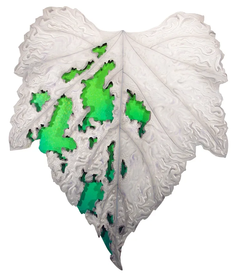 A white leaf carved in relief, with green showing through openings in its surface.