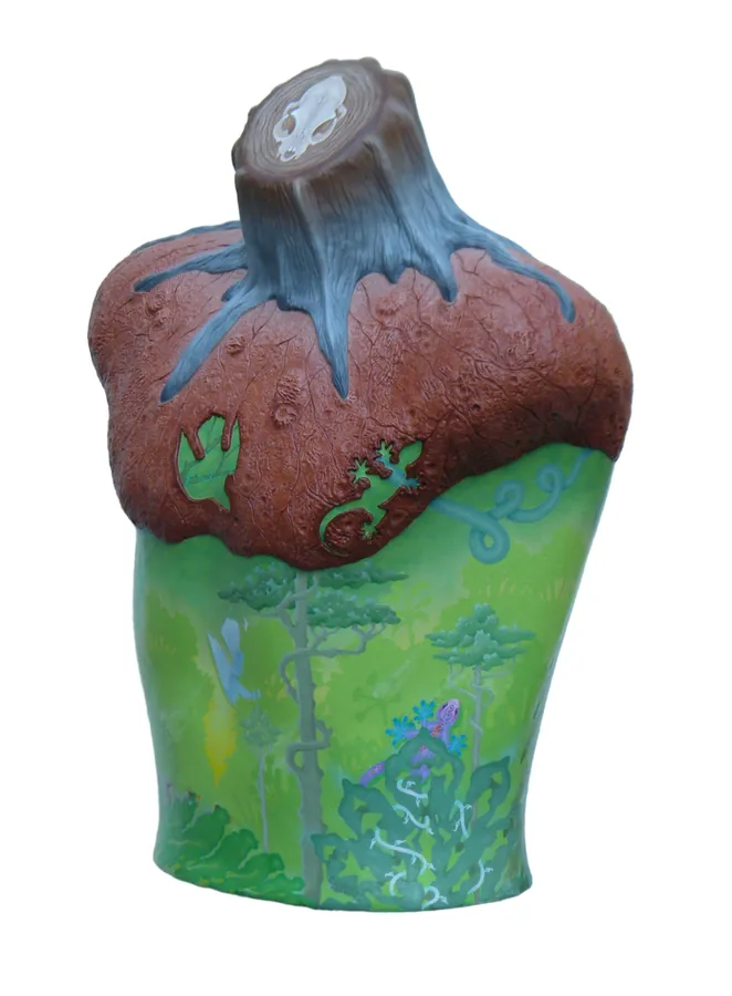 A painted torso form, brown above with green lizards and green below with painted trees, topped by a cut stump.